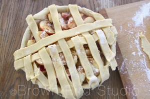 Now, fold the alternating strips back halfway. Place the next pie dough strip across the pie, and fold them down over it.